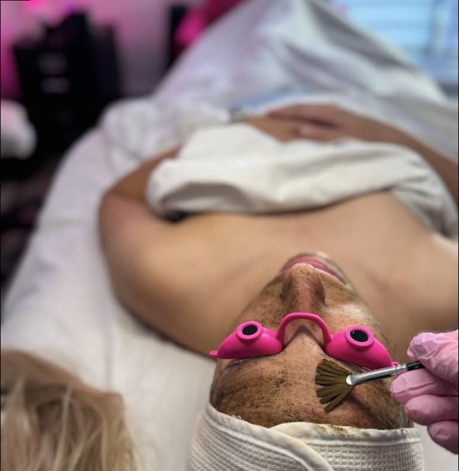 Application d'un soin du visage Anesi Lab au pinceau éventail, cliente allongée sur la table de soin